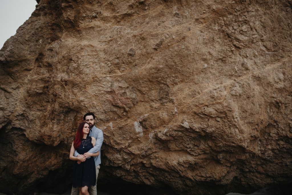 Engaged couple against rocky cliff el matador beach