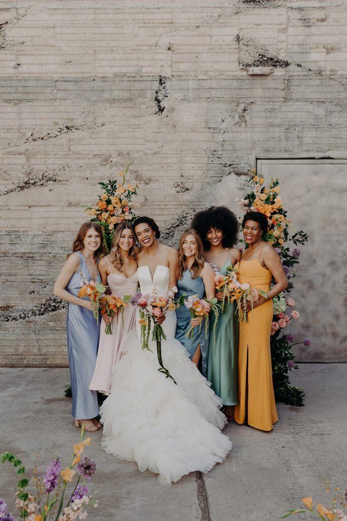 bride smiles with bridesmaids in colorful dresses