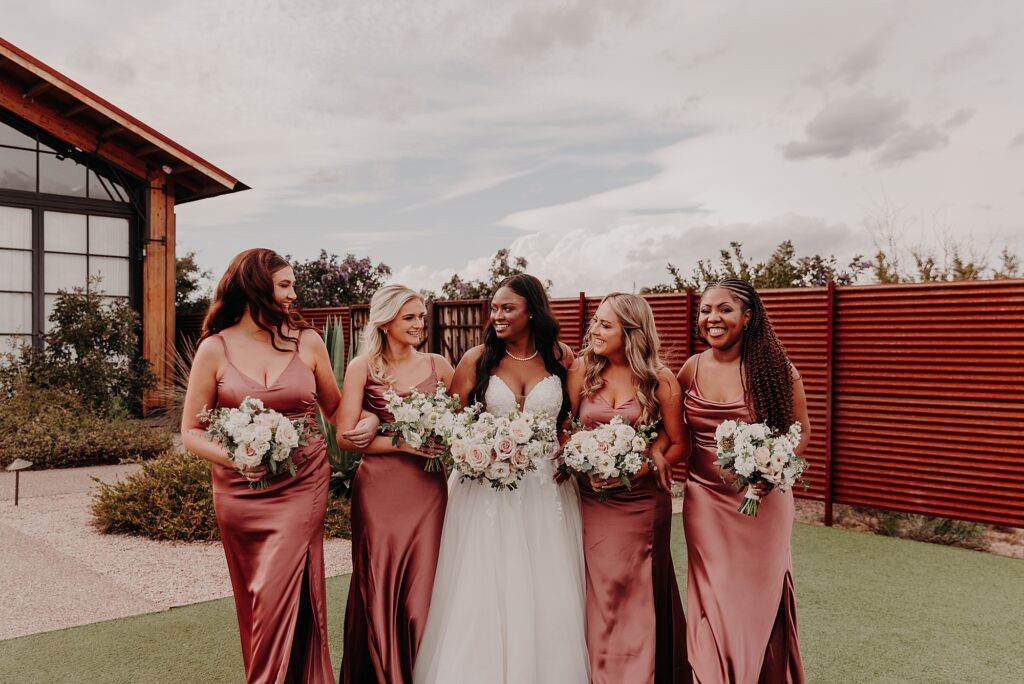 bride and bridesmaids hold bouquets and pose at the paseo wedding venue