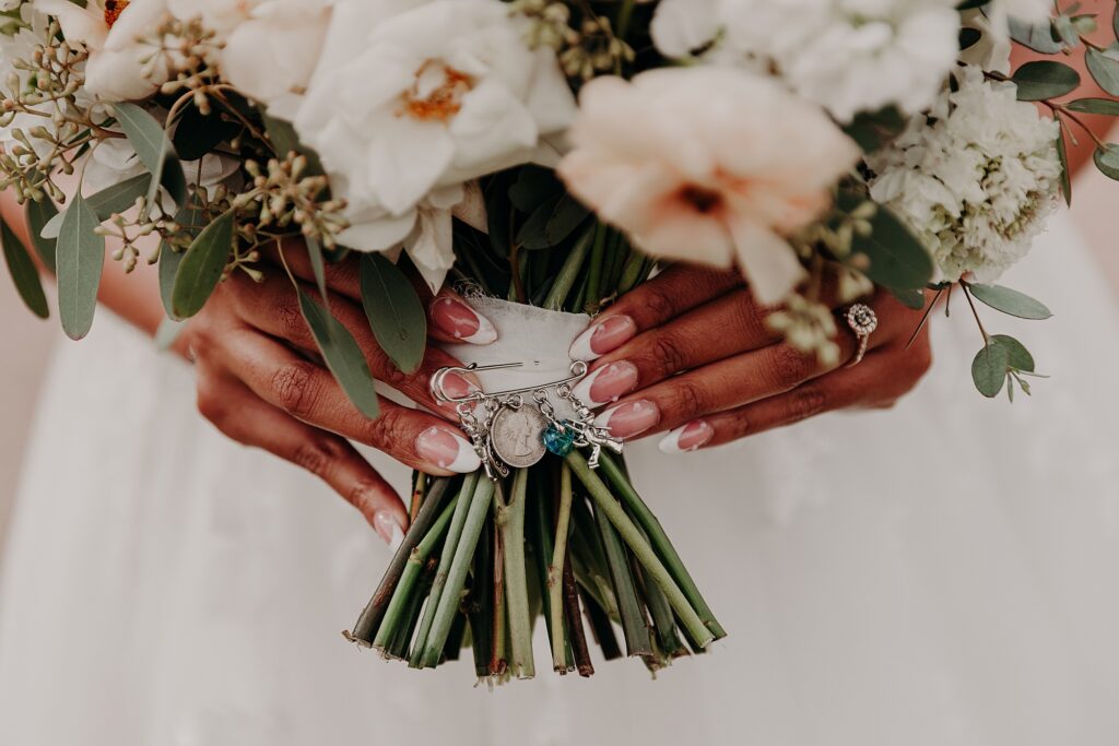 bride hold bouquet that has sentimental pin with charms
