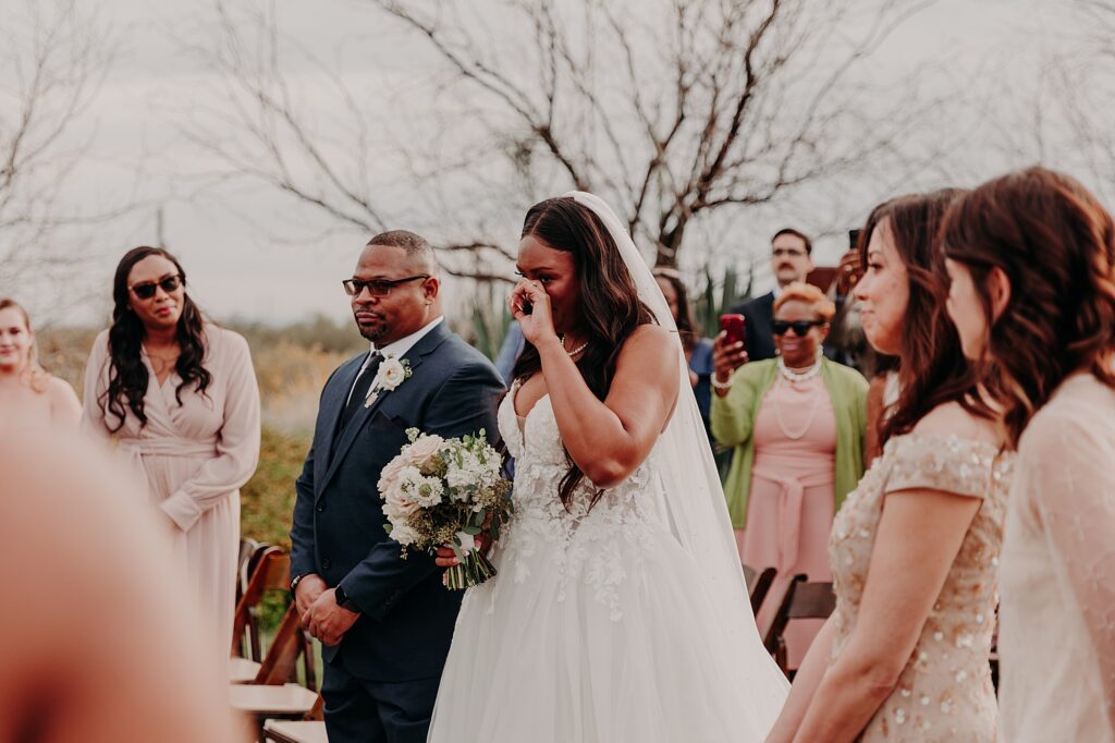bride cries as her father gives her away