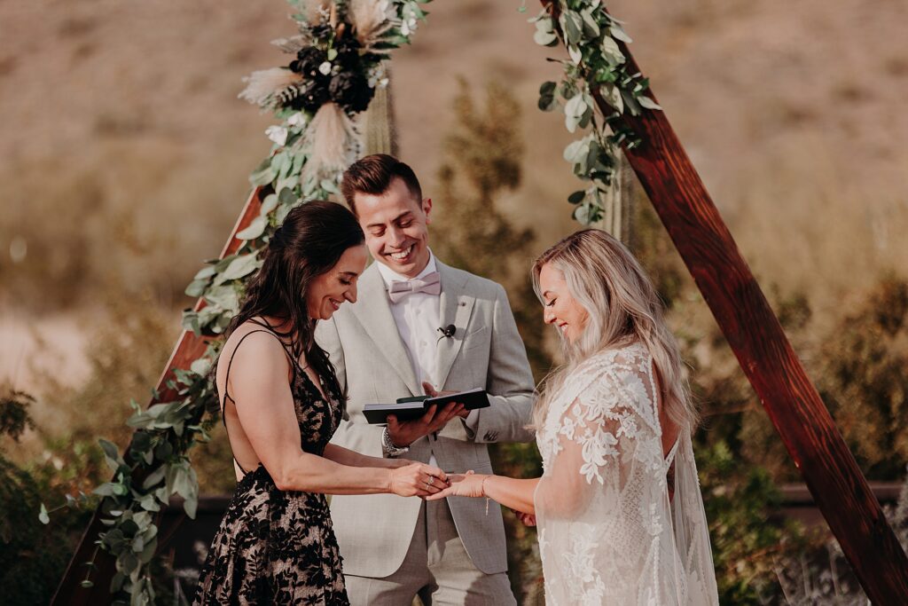 two brides exchange rings during desert ceremony