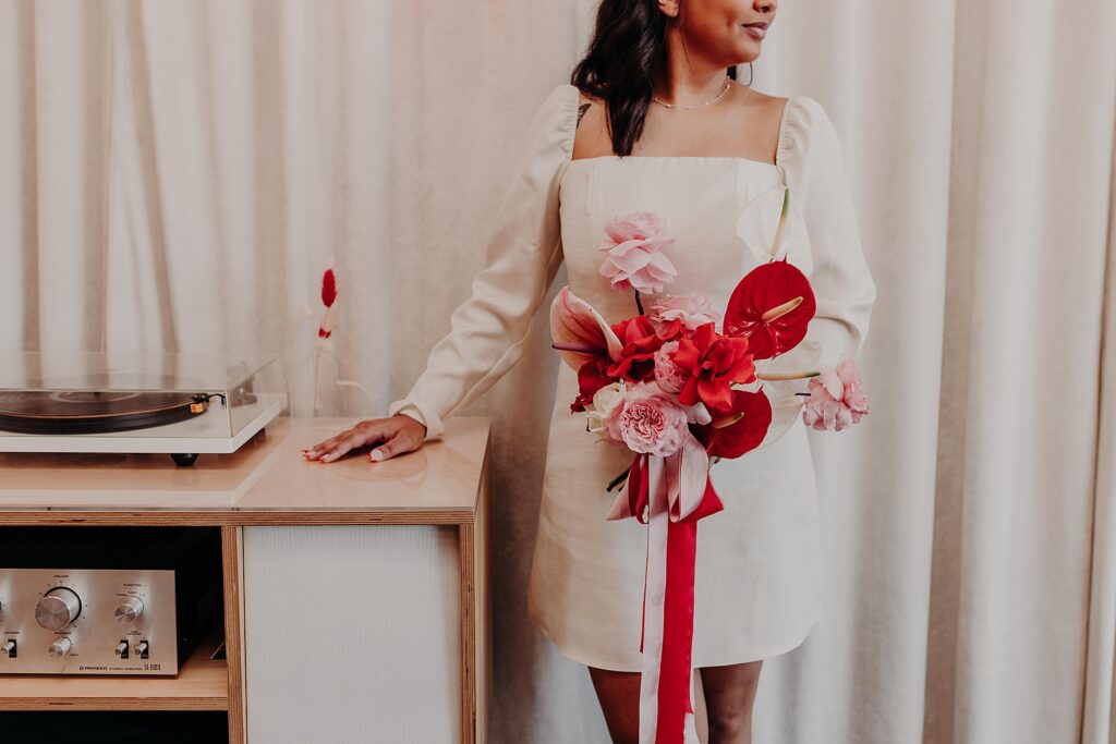 bride poses next to vintage record player on wedding day