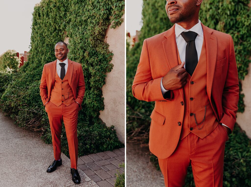 groom stands in terracotta suit with hands in pockets
