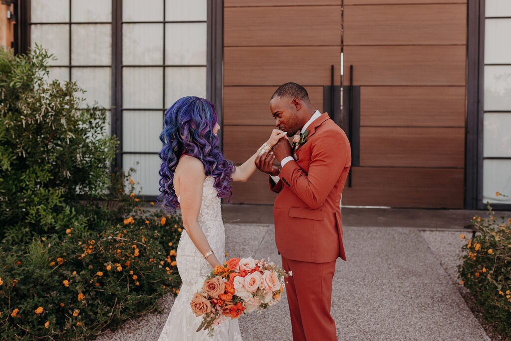 groom holds brides hand and kisses the top of her hand