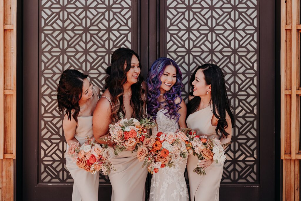 bridesmaids smile and look at one another in front of mosaic designed door