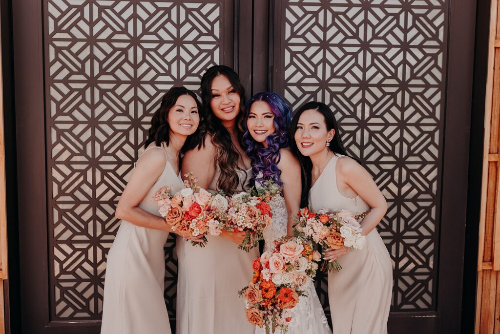 bridesmaids smile and cuddle in front of mosaic designed door