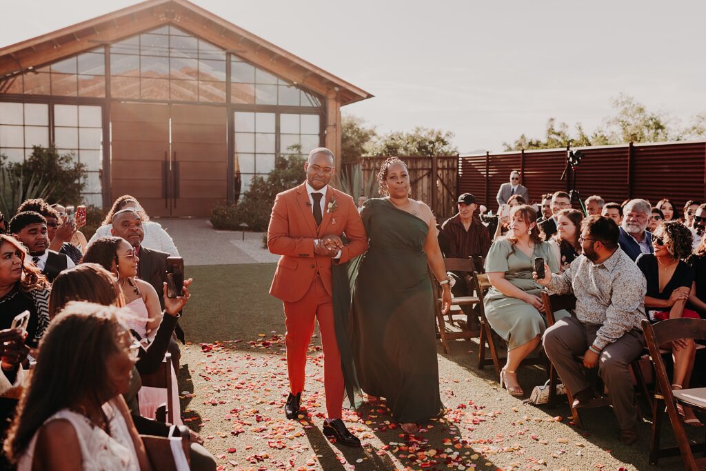 groom and his mother walk down the aisle at wedding ceremony