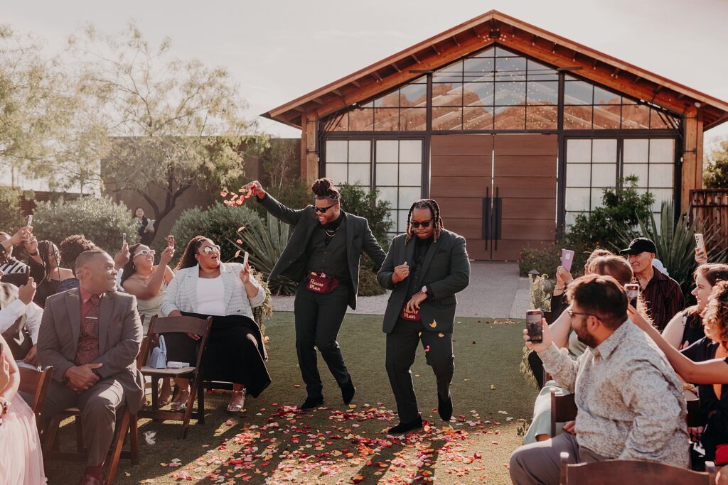 groomsmen walk down the aisle throwing flowers into the aisle
