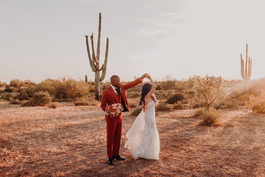 groom spins bride in the desert at sunset