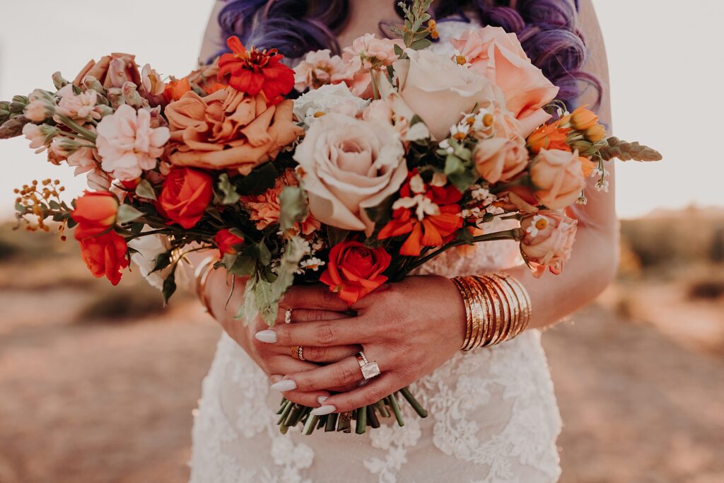 bride holds bouquet while wearing bangles and several rings