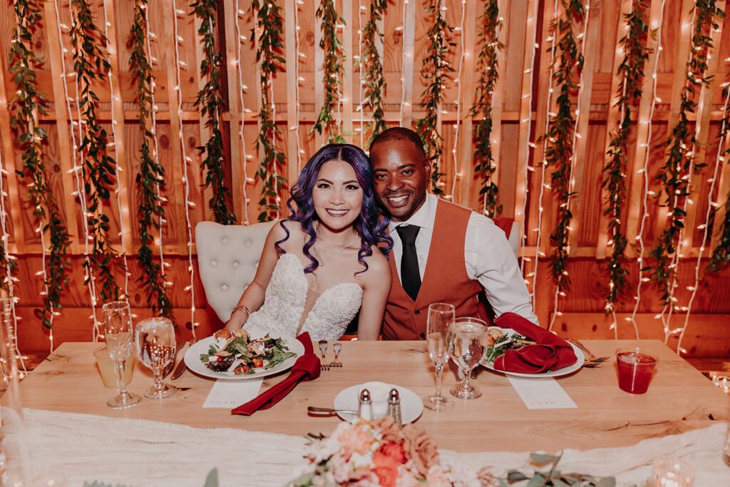 bride and groom smile at their sweetheart table