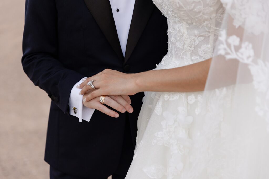 groom holds brides hand on wedding day