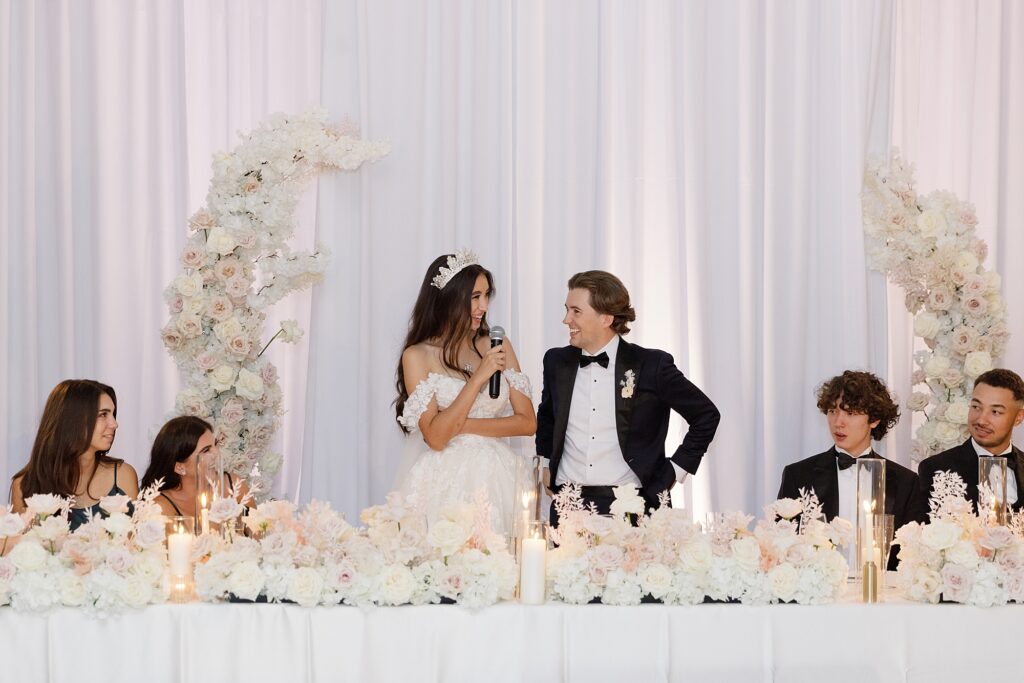 couple share thank you toast on wedding day at sweetheart table