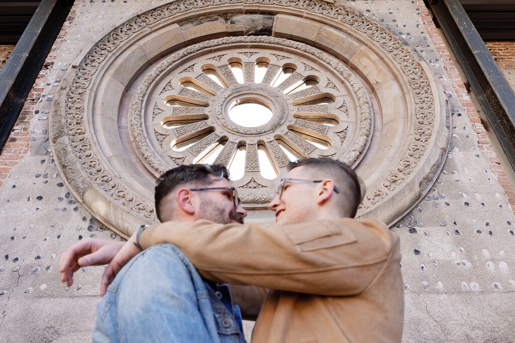 Couple cuddles in front of historic architecture at Monroe Street Abbey in central Phoenix.