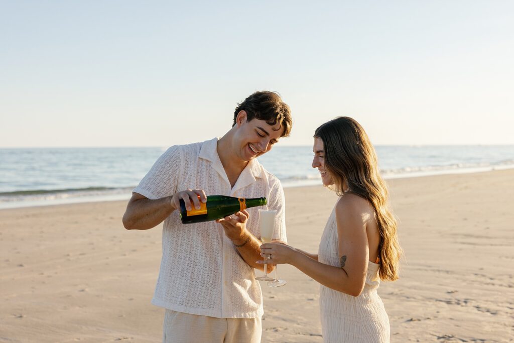 fiance pours champagne after beach proposal