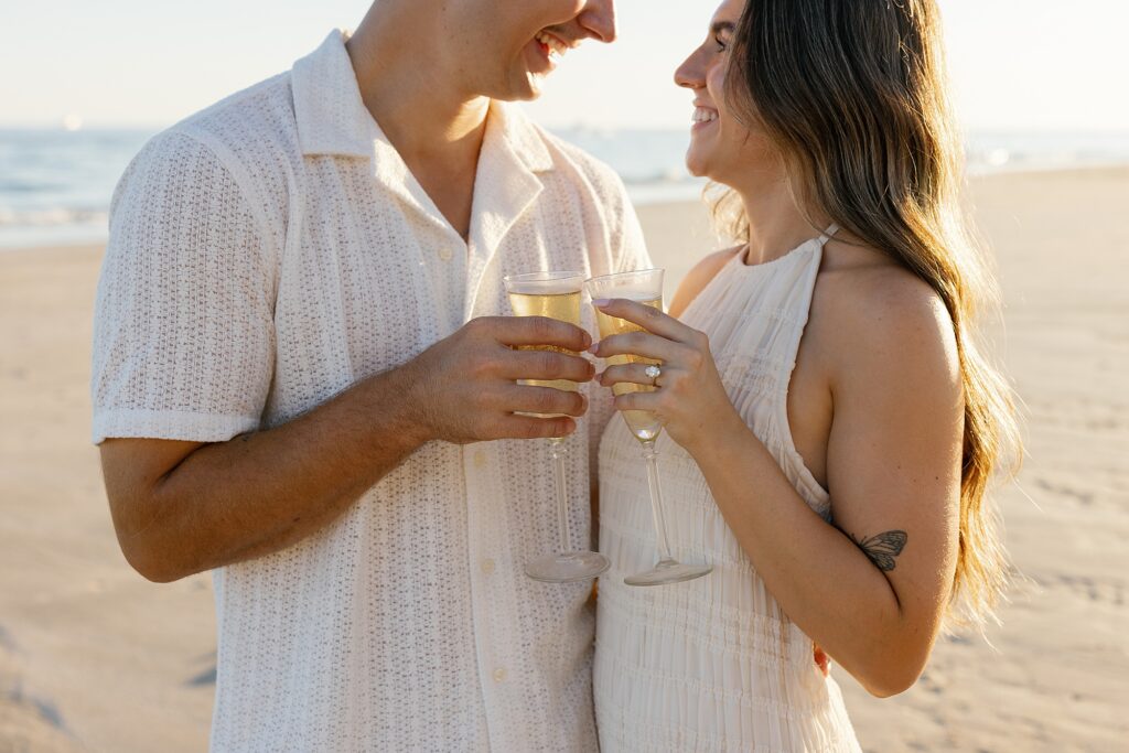 couple celebrate beach proposal with champagne