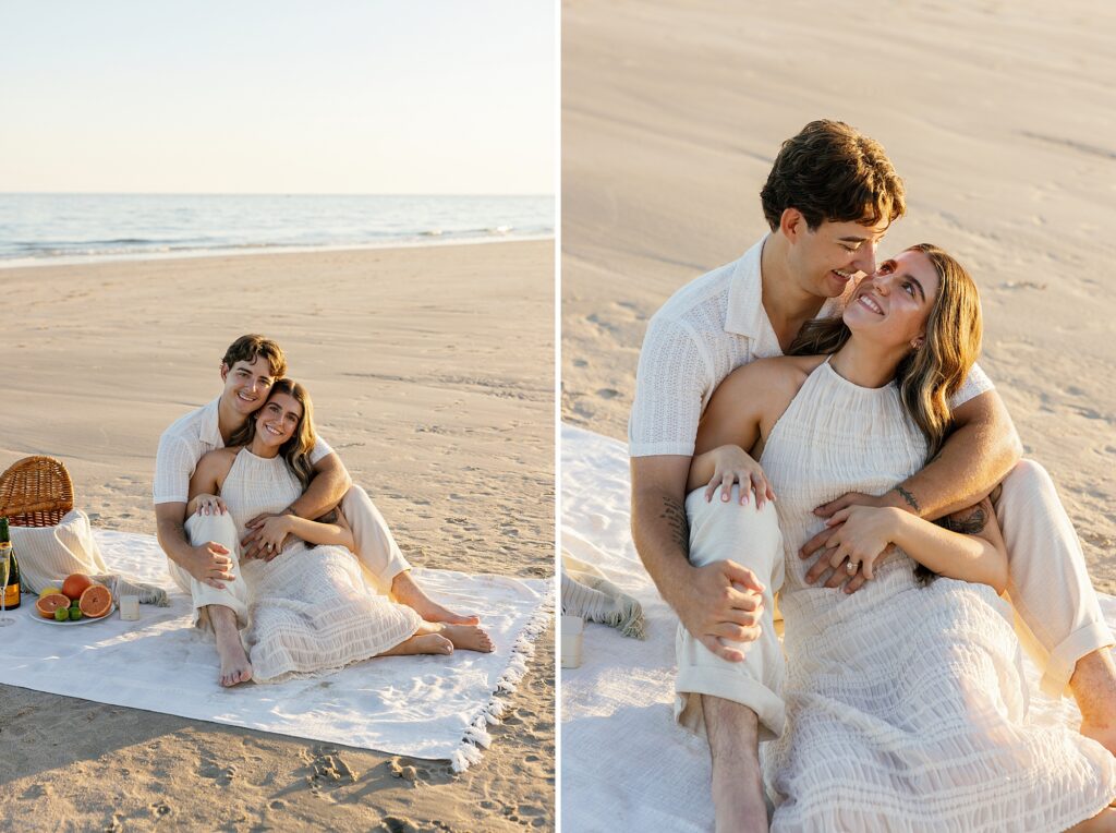 couple cuddle together on a picnic blanket on the beach at sunset