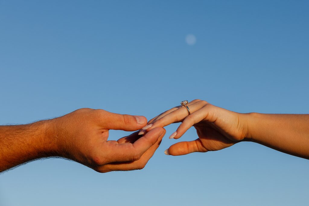 two hands reaching for eachother with the moon in the sky