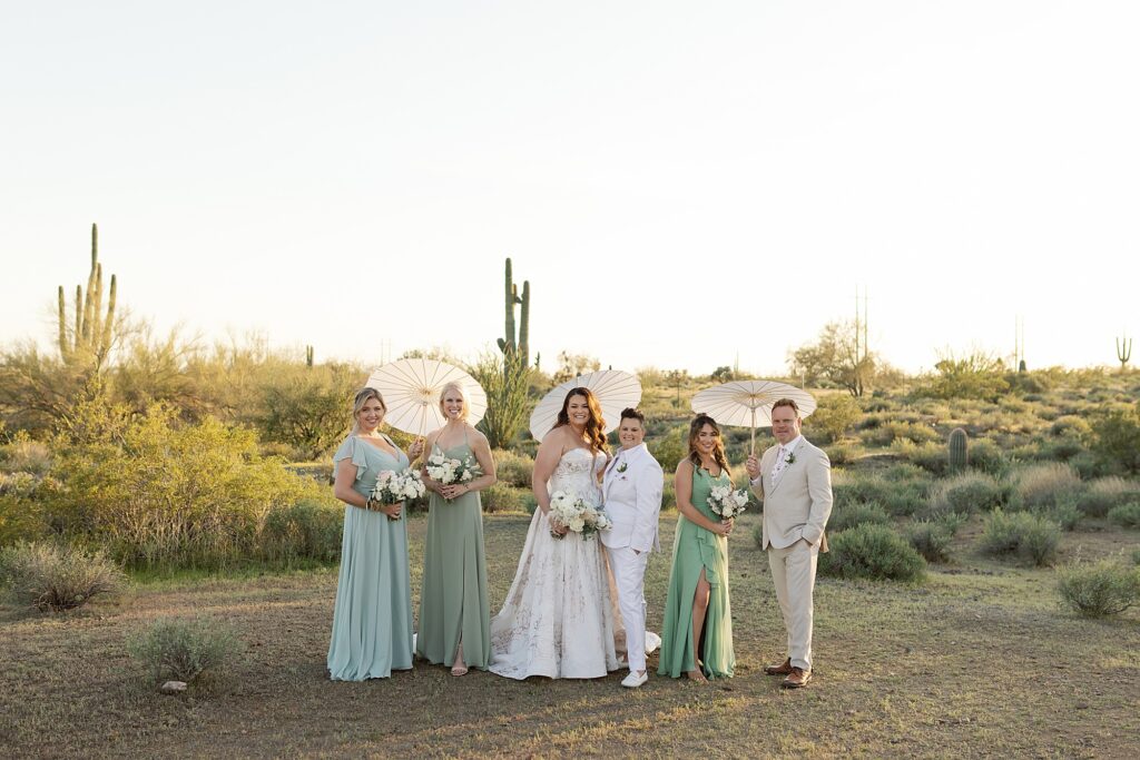 Wedding party in green and white in the Apache Junction desert holding parasols.