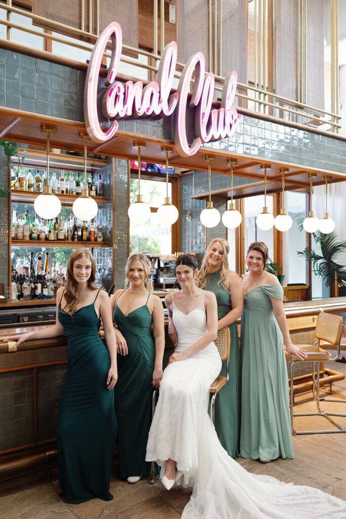Bride and bridesmaids pose against vintage bar at the Canal Club in Scottsdale, Arizona.