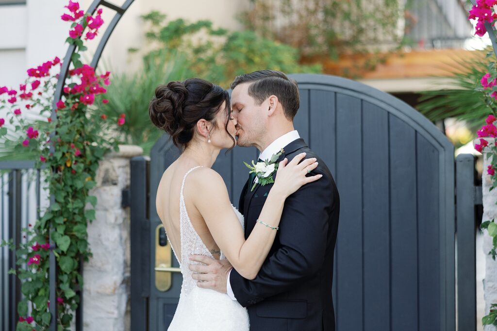 Bride and groom kiss in front of bougainvillea at the Scott Resort and Spa in Scottsdale.