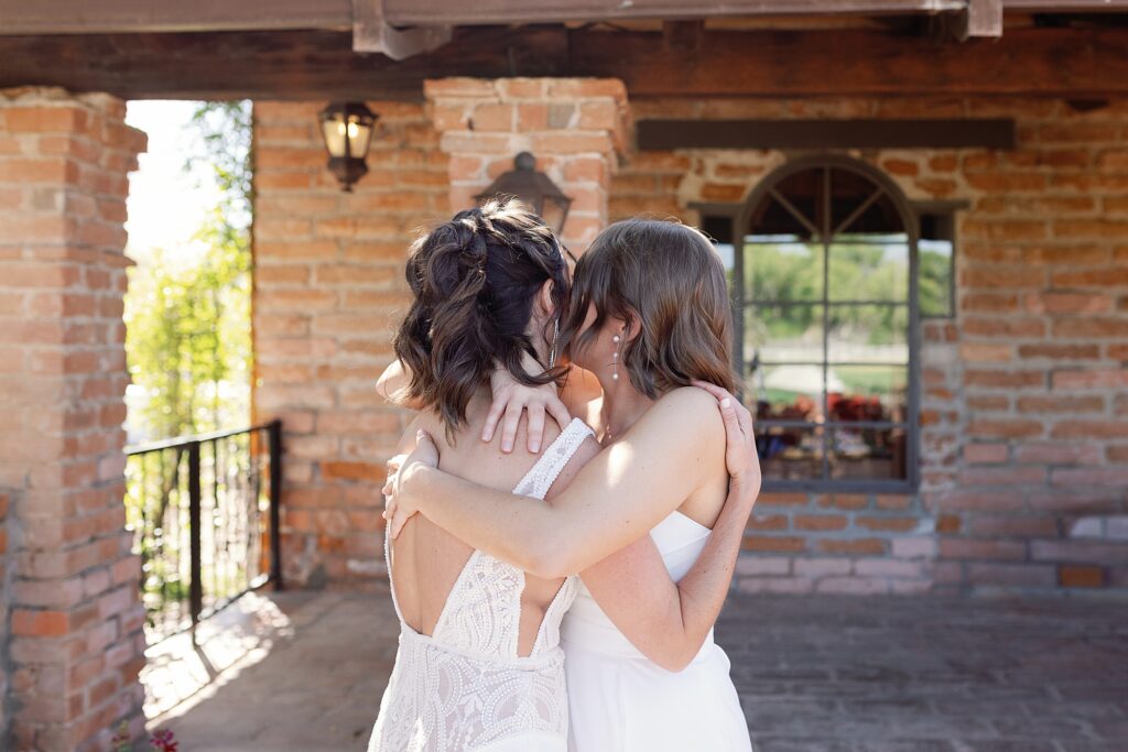 Two brides hug after seeing each other for the first time on wedding day at Tubac Golf Resort.