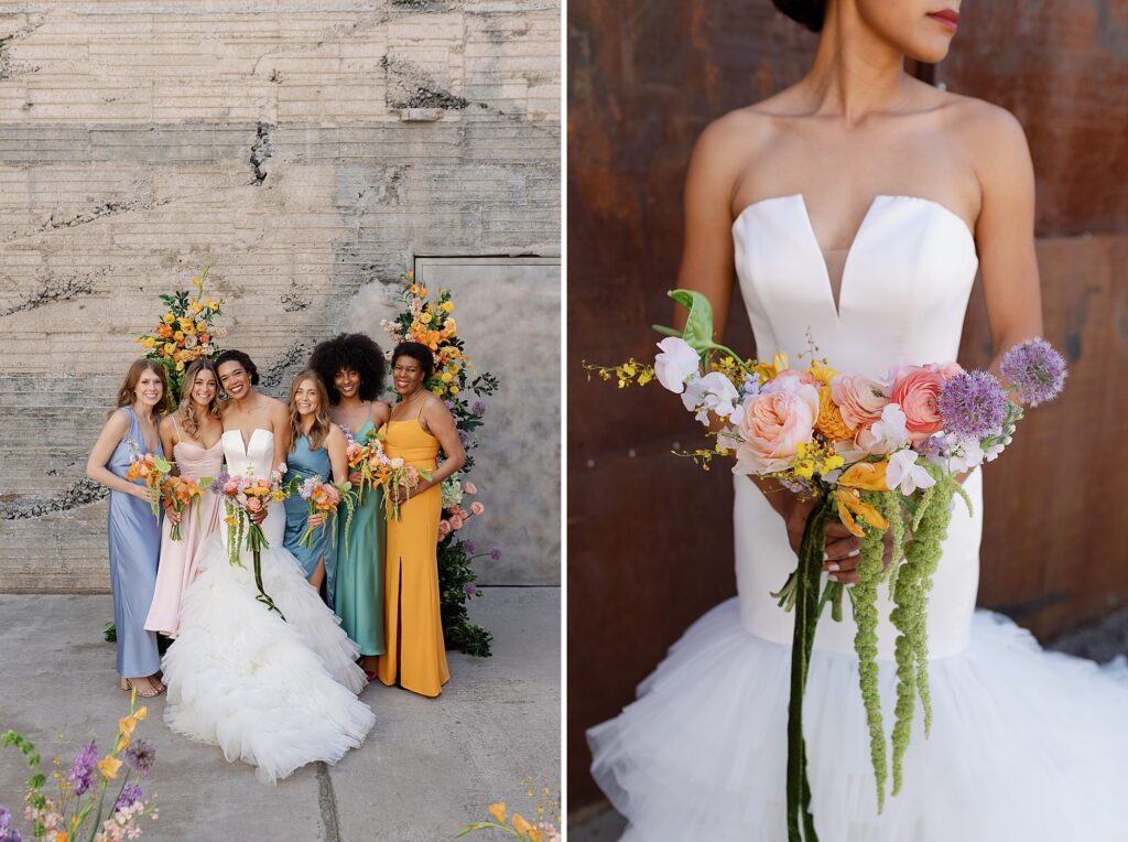 bride and bridesmaids pose and hug in front of industrial wall surrounded by flowers