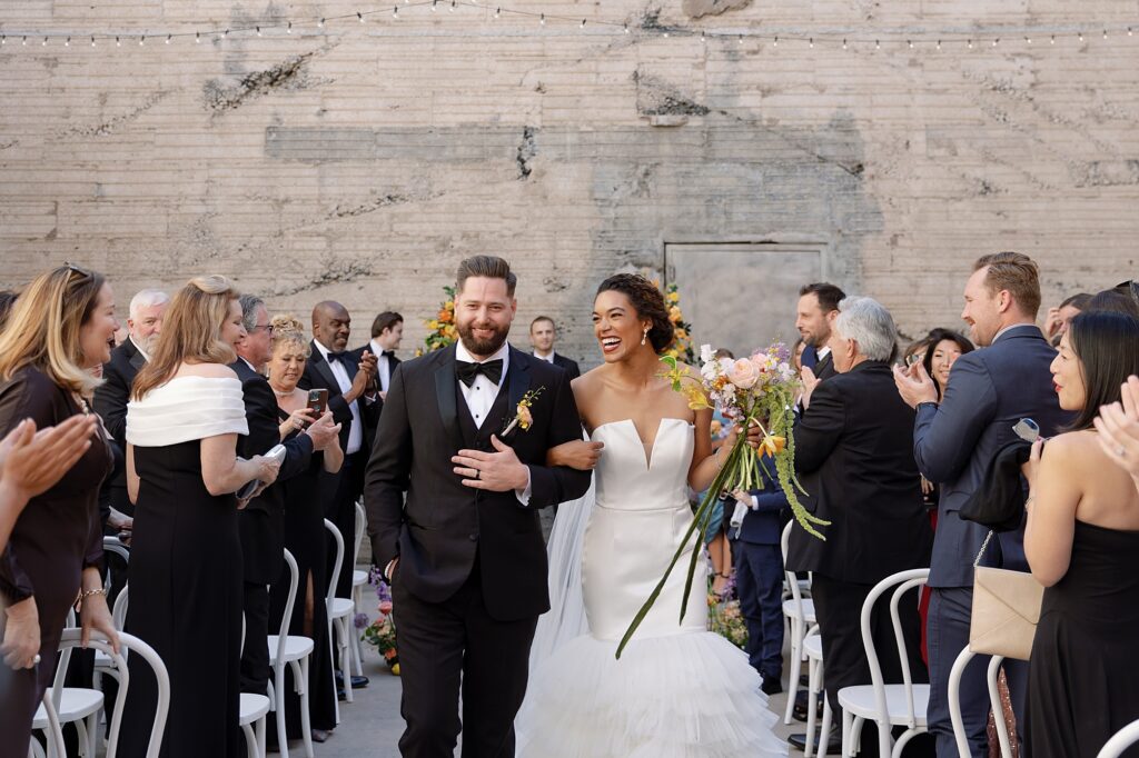 bride and groom walk down the aisle elated