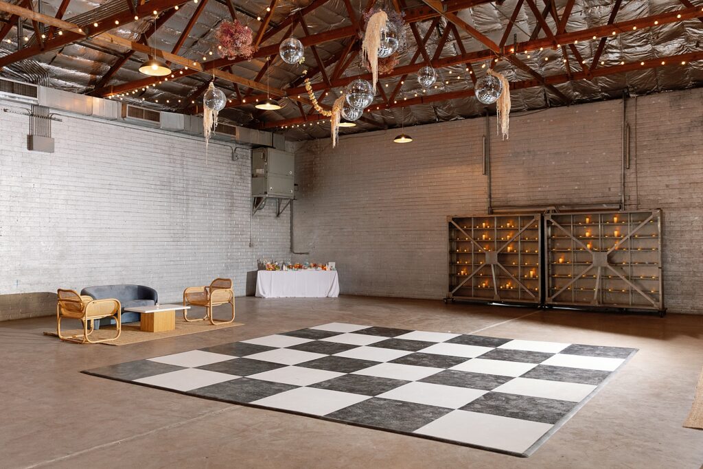 checkered dance floor at wedding in industrial venue with disco balls hanging from ceiling