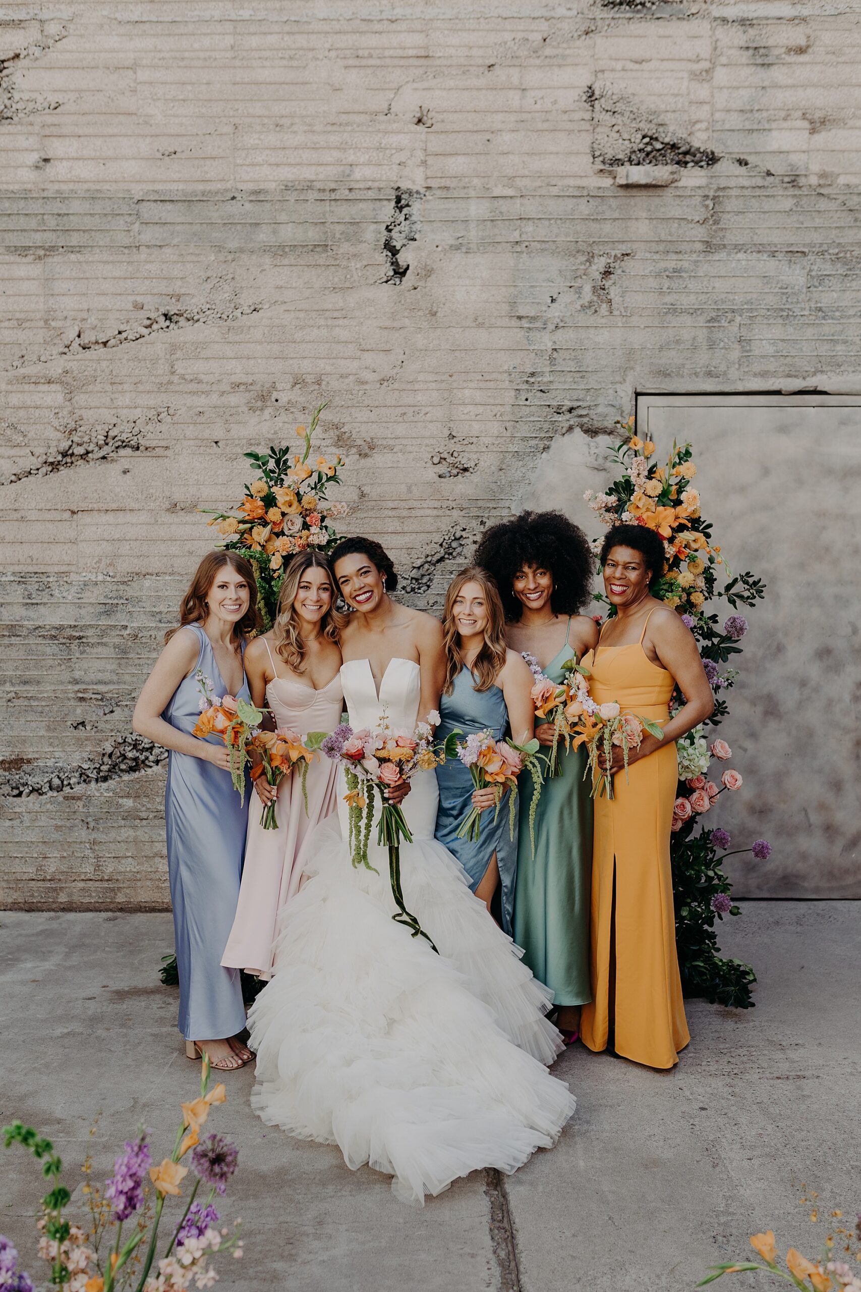 bride smiles with bridesmaids in colorful dresses