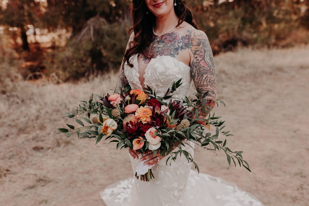 tattooed bride holds bouquet