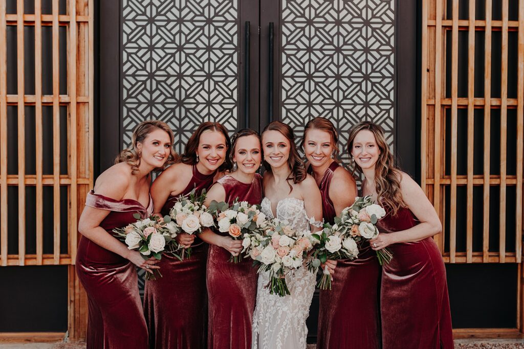 bride and her bridesmaids hold bouquets and smile