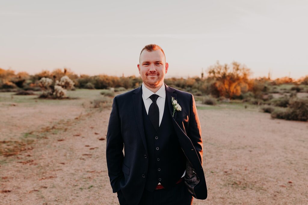 groom poses for the camera during sunset