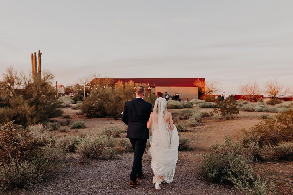 bride and groom walk towards the paseo during sunset