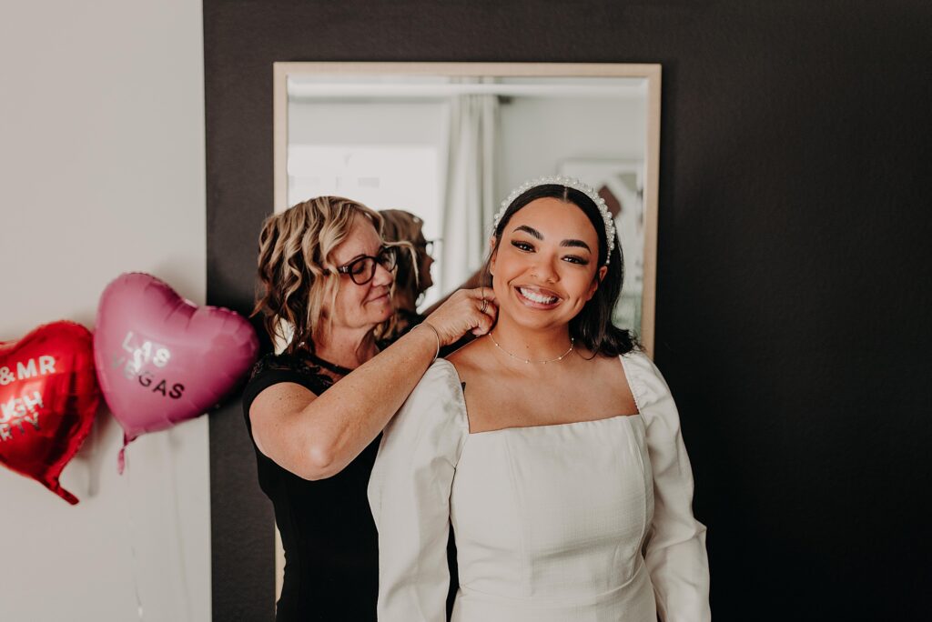 bride's mom putting on her necklace on wedding day