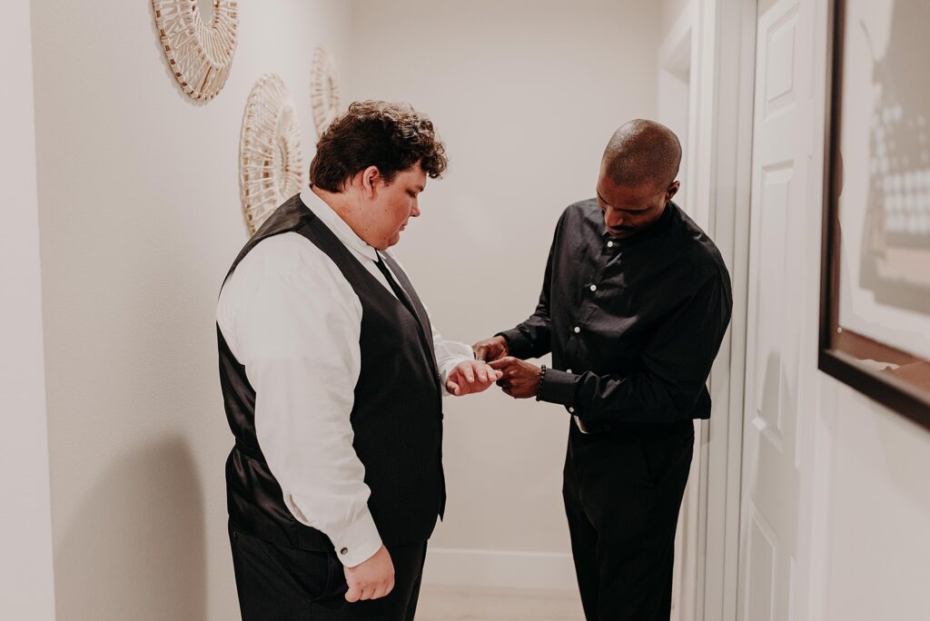 Groom's dad putting on groom's cufflinks