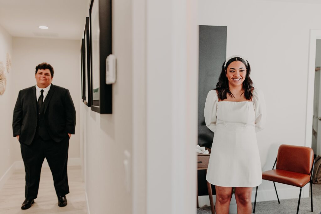Bride and groom stand on opposite sides of doorway before seeing one another