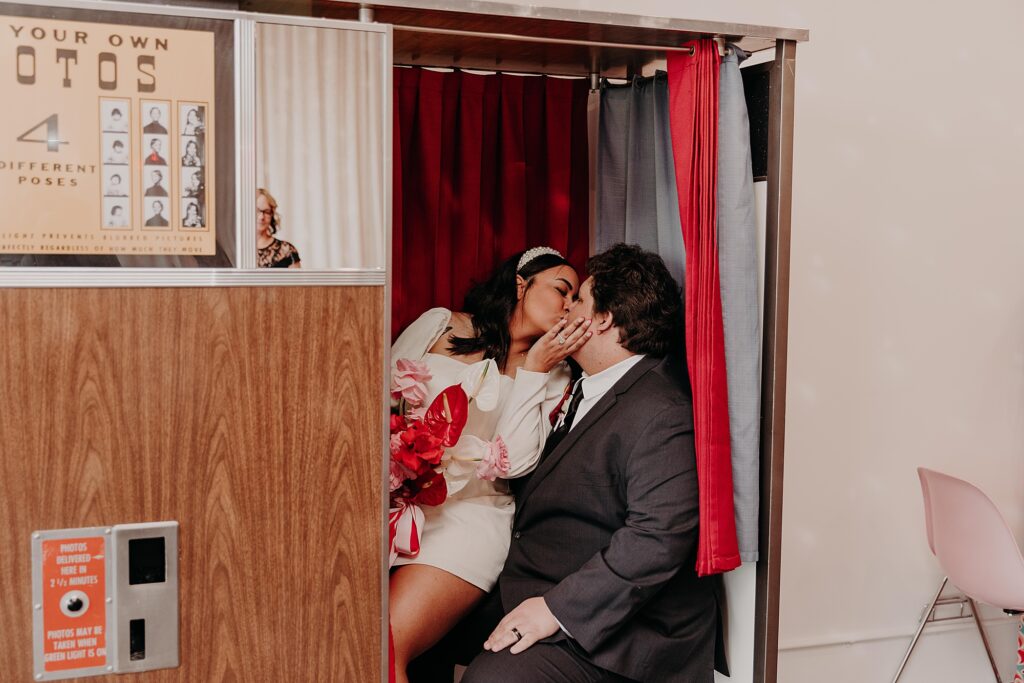 bride and groom sit in vintage Photo Booth after wedding ceremony