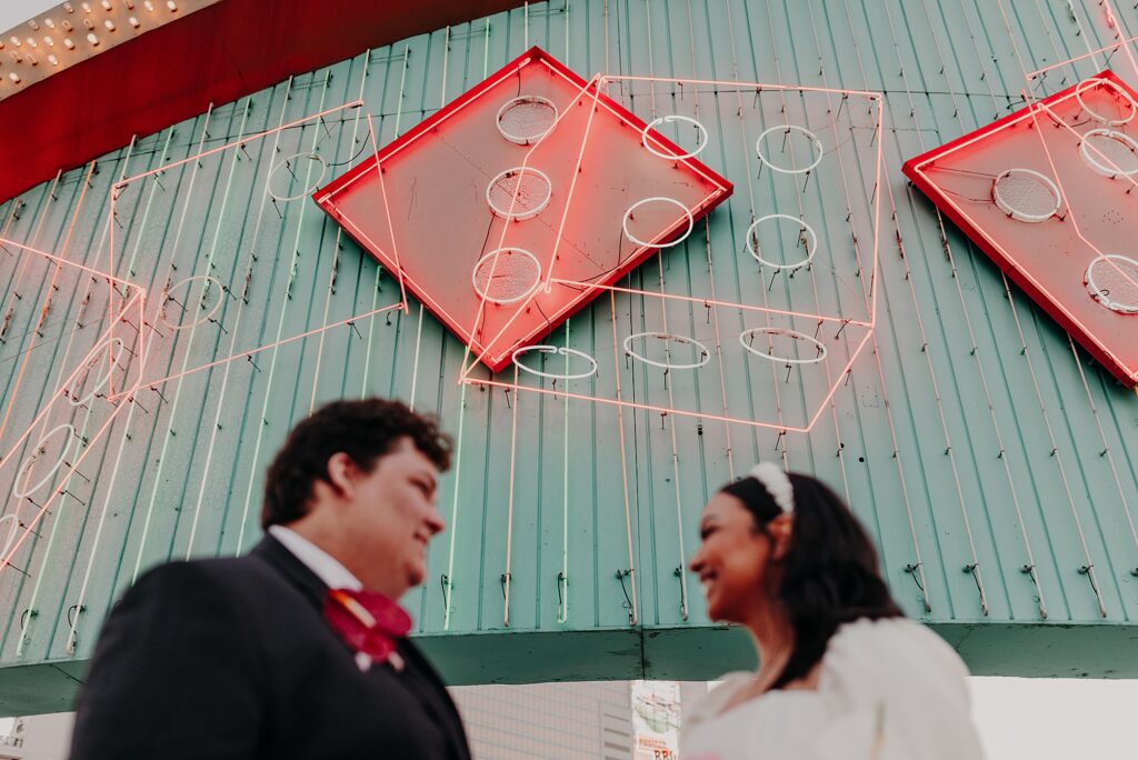 bride and groom stand in front of neon lights on vegas rooftop