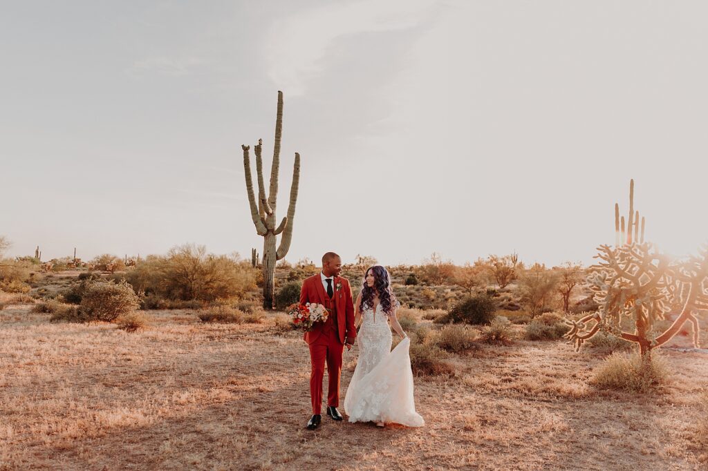bride and groom walking together holding hands in the desert